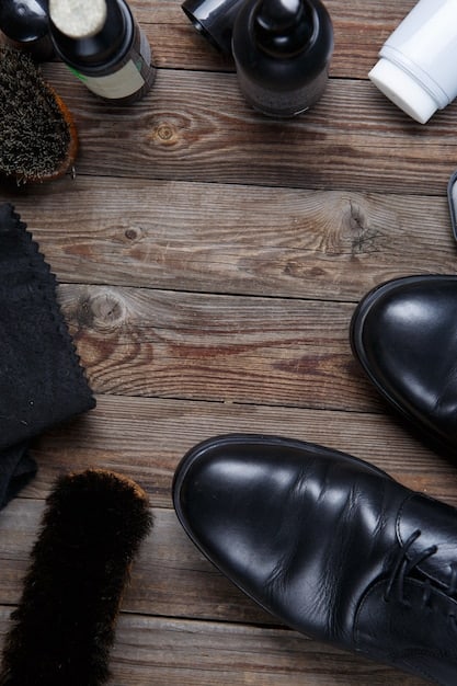 A pair of highly polished black leather oxford shoes, gleaming, next to a variety of leather care products including a cleaning brush, conditioning cream, and a polishing cloth.