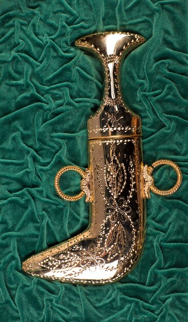 A close-up shot of a luxurious, dark green velvet boot with intricate gold embroidery and a comfortable block heel. The texture of the velvet is highly detailed, emphasizing warmth and richness.