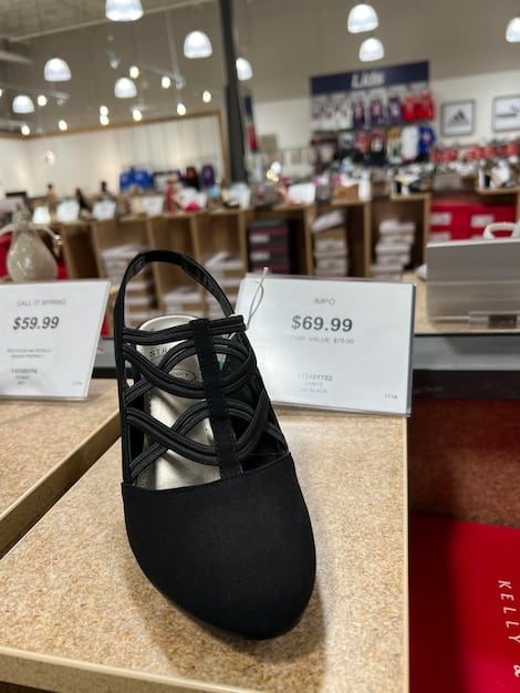 A close-up of a designer shoe rack at a well-organized sample sale, with various shoe styles neatly displayed and discount signs visible.