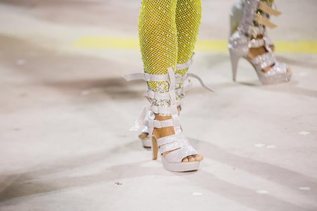 A detailed shot of designer shoes on a runway model during a Spring/Summer 2025 fashion show, highlighting bold, trend-setting colors and innovative designs.