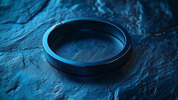 A close-up of a titanium ring with a vibrant blue anodized finish, showcasing its smooth texture and light-reflecting properties. The ring is set against a blurred background, emphasizing its unique color.