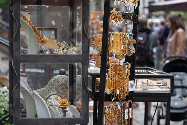 A bustling high-street jewelry boutique, with display cases showcasing various pieces of fashion jewelry under warm, inviting lights. Sales associates are tending to customers, and the store atmosphere is clean and upscale, illustrating the costs associated with prime retail space and customer experience.