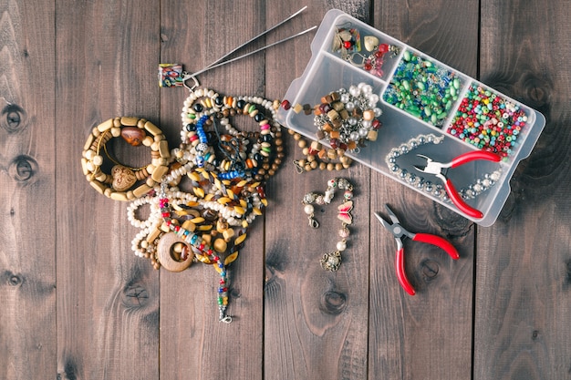 A neatly organized workbench with various jewelry components, including loose beads, chains, small pliers, and wire, suggesting the deconstruction and sorting process.