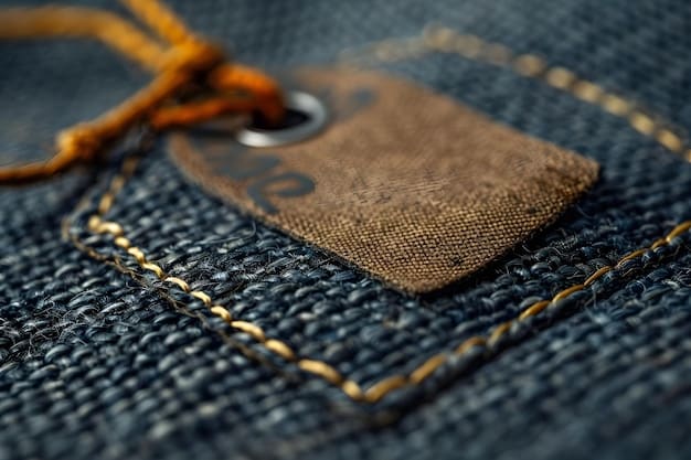 A close-up of a premium denim brand tag on a pair of jeans, highlighting the stitching and fabric texture, with a blurred background of other denim on a rack.