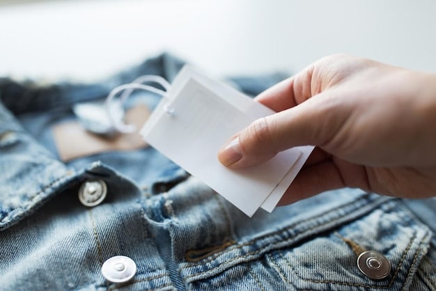 A detailed hand holding a clothing tag with return policy information clearly visible, against a backdrop of neatly folded outlet clothing.