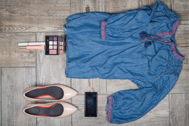 A detailed flat lay of a stylish plus-size outfit composed of items that could be found at an outlet: a striped top, distresses jeans, comfortable sneakers, a stylish handbag, and delicate accessories, all neatly arranged on a light-colored surface.