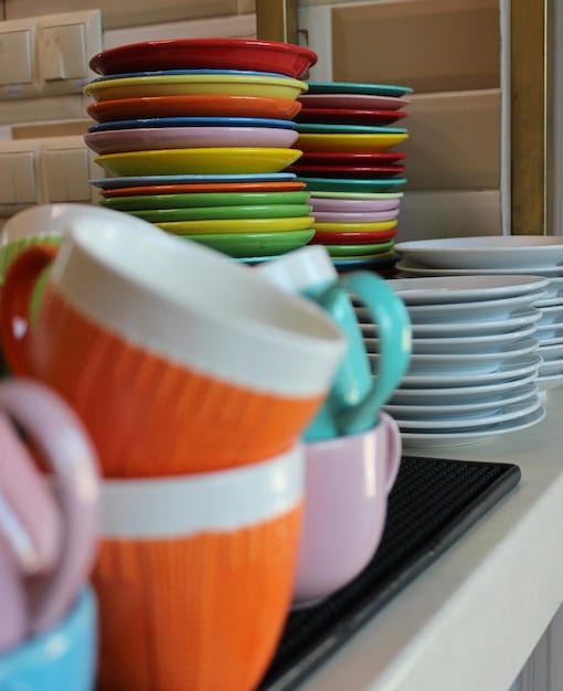A close-up of a neatly arranged display of colorful kitchen essentials and dinnerware sets in an outlet store, suggesting variety and affordability.