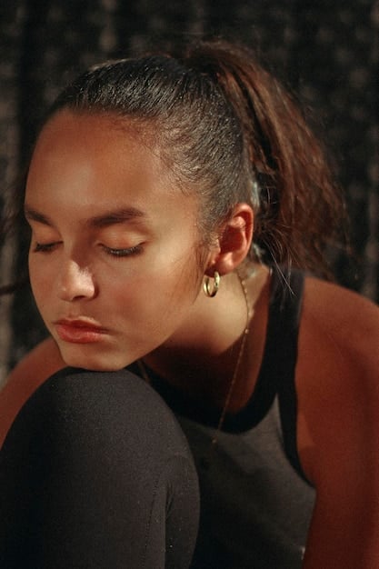 A close-up of a model wearing large, gold-textured hoop earrings with a subtle hammered finish, her hair pulled back to highlight the jewelry. Sunlight catches the metal, creating a warm glow.