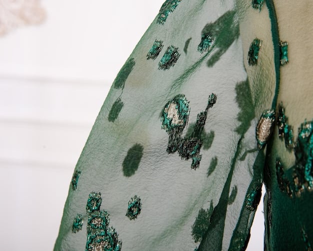 A close-up shot of a silk scarf featuring a delicate, abstract watercolor print in shades of soft blue, green, and coral, draped elegantly over a pristine white blazer.
