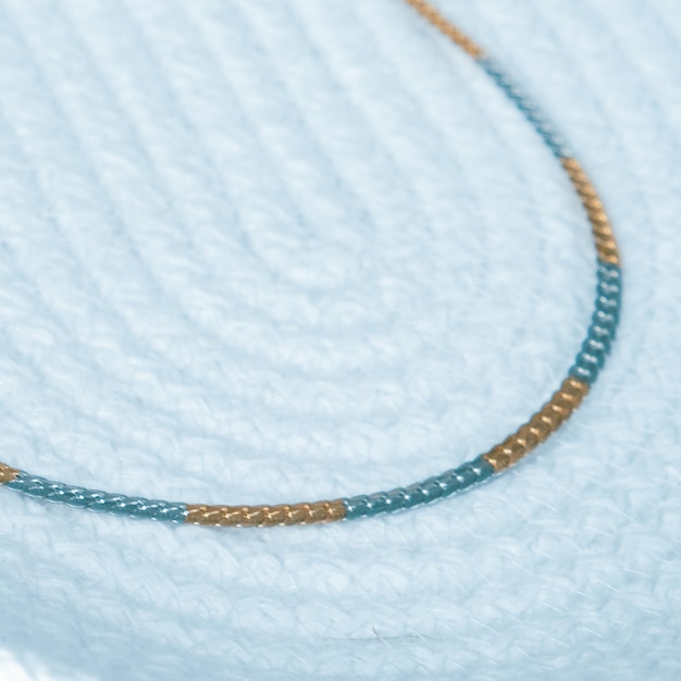 A close-up shot of a minimalist layered necklace combination featuring three delicate gold chains with small, understated pendants, resting on light-colored fabric.