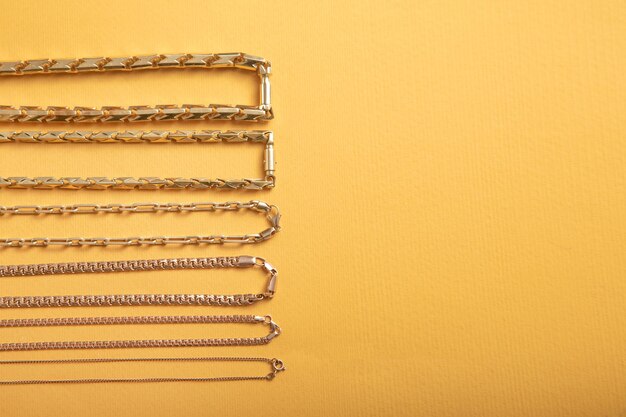 A detailed flat lay showing a curated selection of jewelry-making components, including various chain types, pendants, jump rings, and clasps, on a light-colored surface.