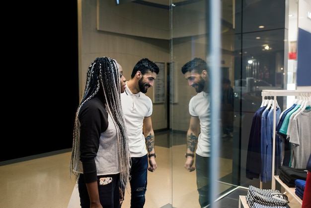 A diverse group of people browsing through racks of designer clothes in a brightly lit, spacious outlet store, with clear signage indicating sales percentages.